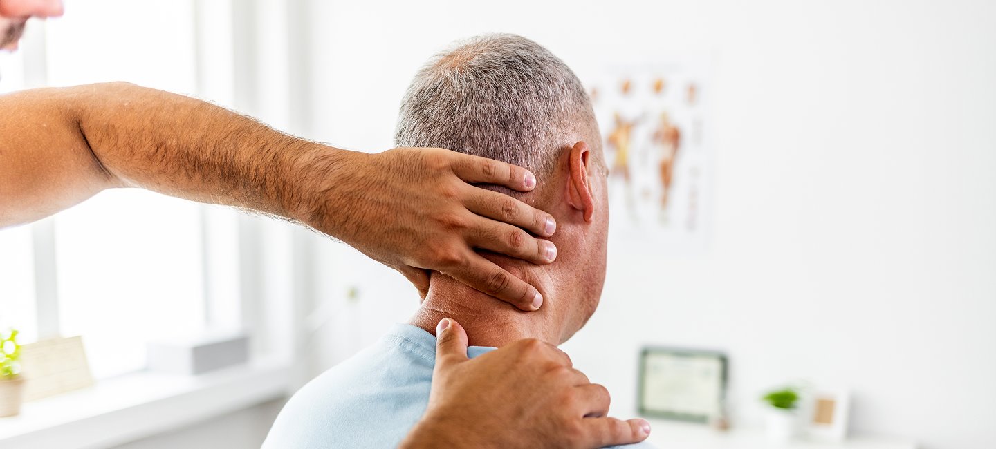 A therapist examining and gently adjusting the neck of an older man