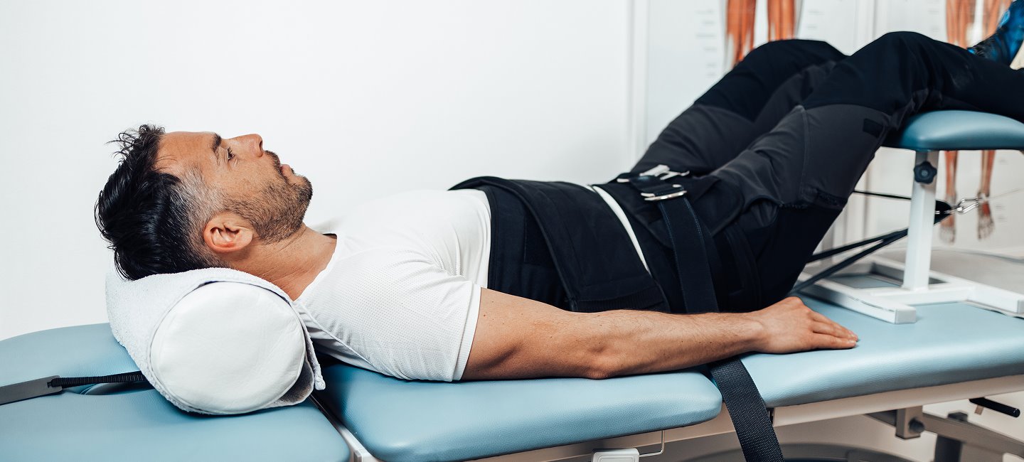 Man receiving spinal decompression therapy while lying on a treatment table