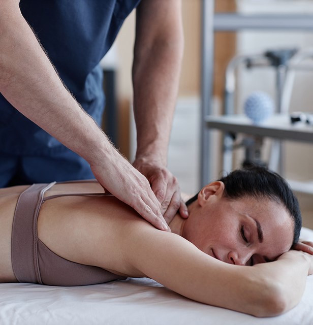 A therapist pressing on a woman’s upper back and shoulders